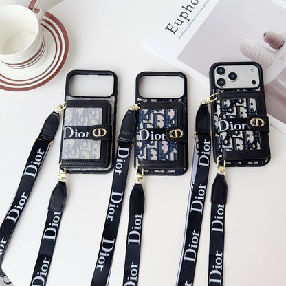 Three Dior phone cases with lanyards on a white surface with a magazine and cup.