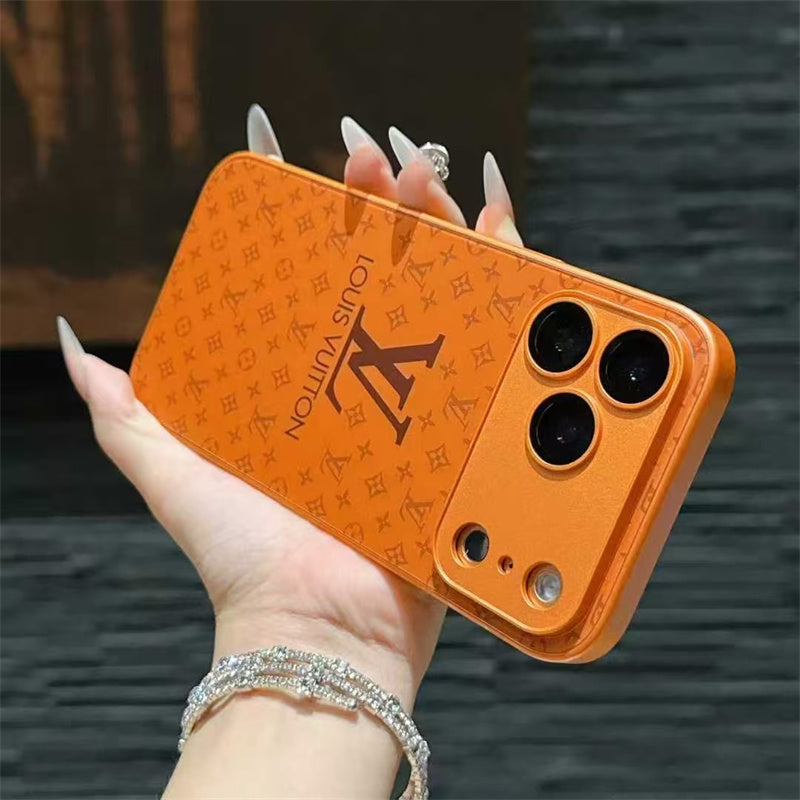 Orange phone case with a brand logo held by a hand against a dark background